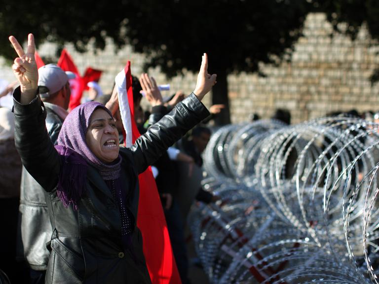 Januar 2011 in Tunis / Tunesien: Eine Demonstrantin mit Kopftuch fordert lautstark Soldaten auf, sie durch die Stacheldrahtbarrikade vor dem Büro des tunesischen Premierministers zu lassen. 