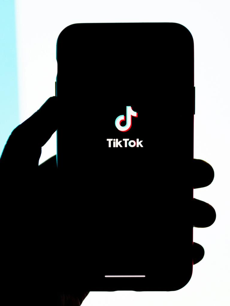 Silhouette einer Hand, die ein Smartphone mit einem TikTok-Logo auf dem Screen, hält