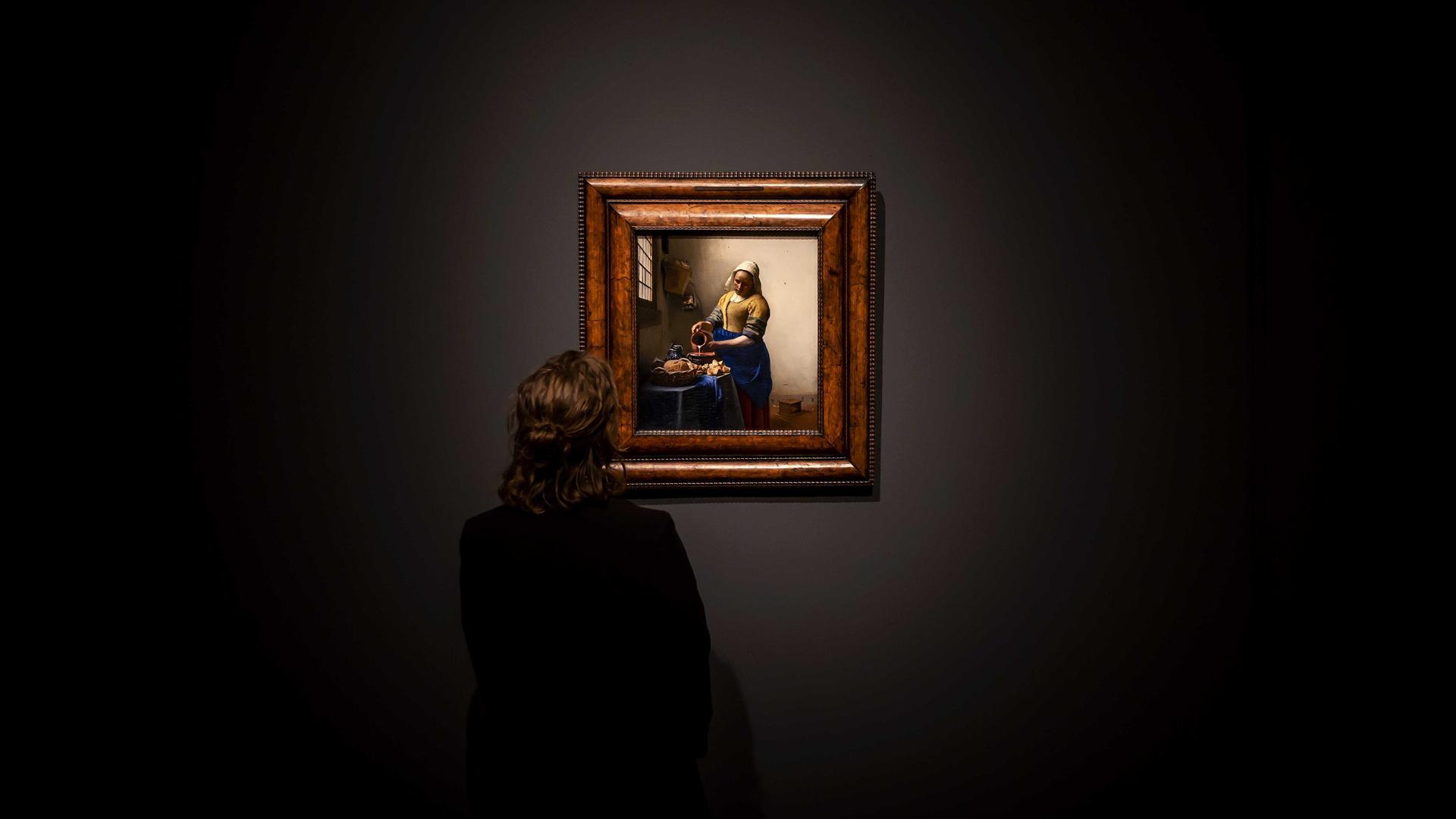 Ein Museumsangestellter steht vor dem Gemälde "Dienstmagd mit Milchkrug" von Jan Vermeer in der Eremitage Amsterdam. 