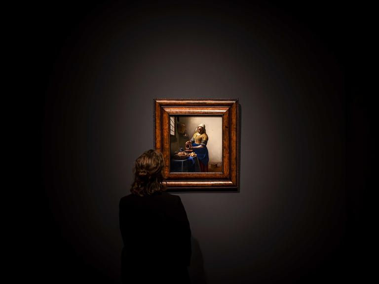 Ein Museumsangestellter steht vor dem Gemälde "Dienstmagd mit Milchkrug" von Jan Vermeer in der Eremitage Amsterdam. 