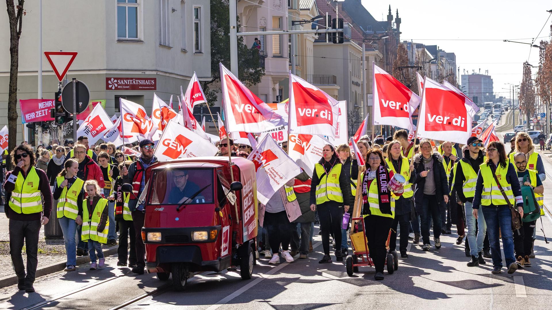 Mehrere hundert Menschen sind in Cottbus einem Aufruf der Gewerkschaft ver.di gefolgt und bilden eine Menschenschlange, sie tragen Fahnen mit der Aufschrift "Verdi".