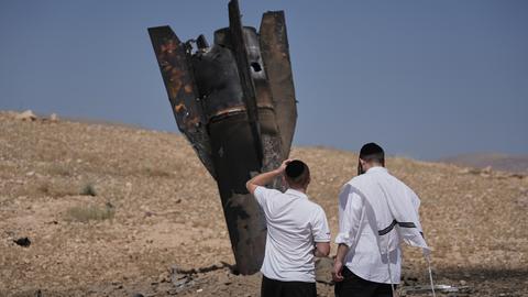 Zwei Menschen stehen vor den Trümmern einer iranischen Rakete, die in der Nähe der Hebron im Westjordanland gelandet sind
