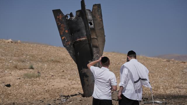 Zwei Menschen stehen vor den Trümmern einer iranischen Rakete, die in der Nähe der Hebron im Westjordanland gelandet sind