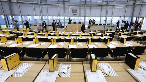 Das Bild zeigt einen Blick in den Plenarsaal. Zu sehen sind die Sitzreihen und Unterlagen auf den Tischen.