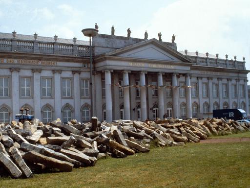 Zum  Start der" documenta 7" ließ Joseph Beuys 7.000 Basaltstelen alsDreieck auf dem Friedrichsplatz in Kassel aufhäufen. An dessen Spitze pflanzte er die erste von 7.000 Eichen