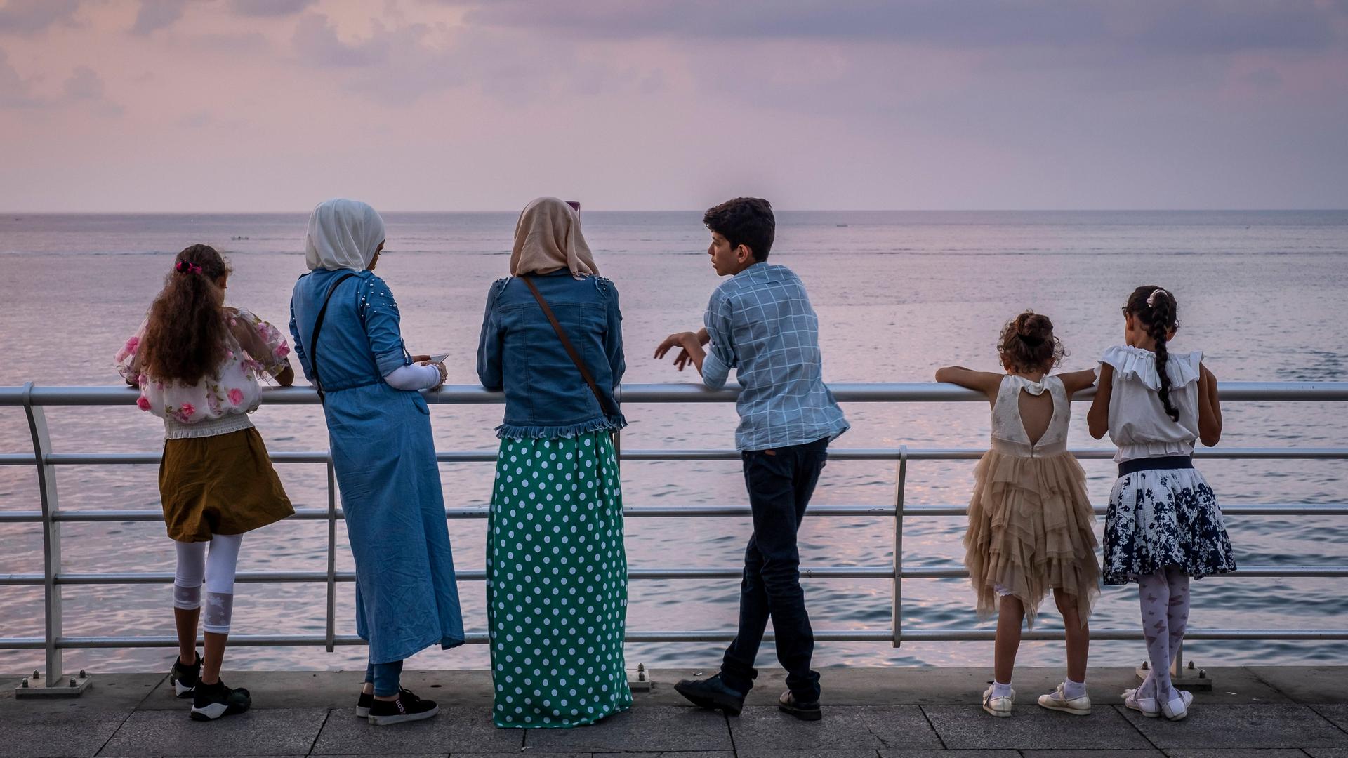 Junge Menschen stehen an der Strandpromenade in Beirut und blicken aufs Meer.