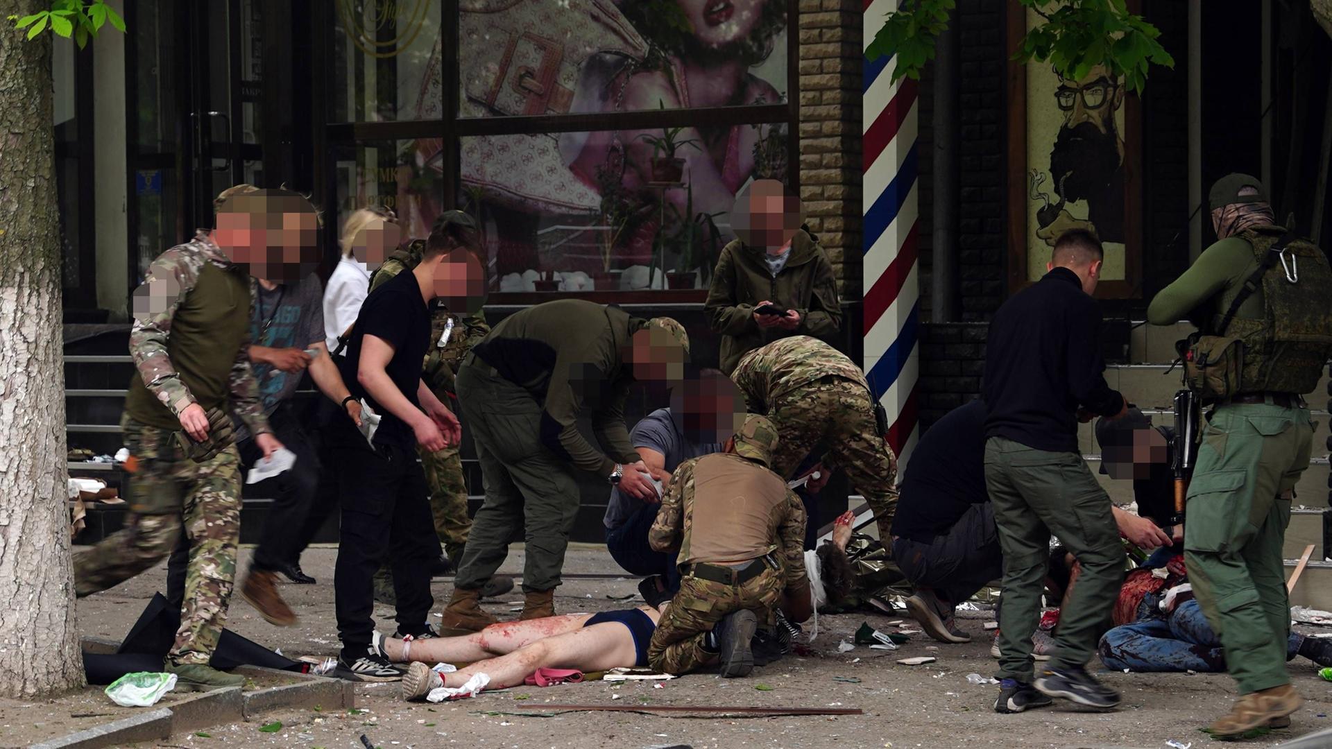Ukraine, Luhansk: In einem Frisörladen detonierte eine Bombe. Helfer und eine Verletzte Person am Boden liegend sind zu sehen.