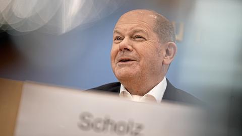 Der SPD-Politiker und Bundeskanzler Olaf spricht bei einer Pressekonferenz und lächelt.