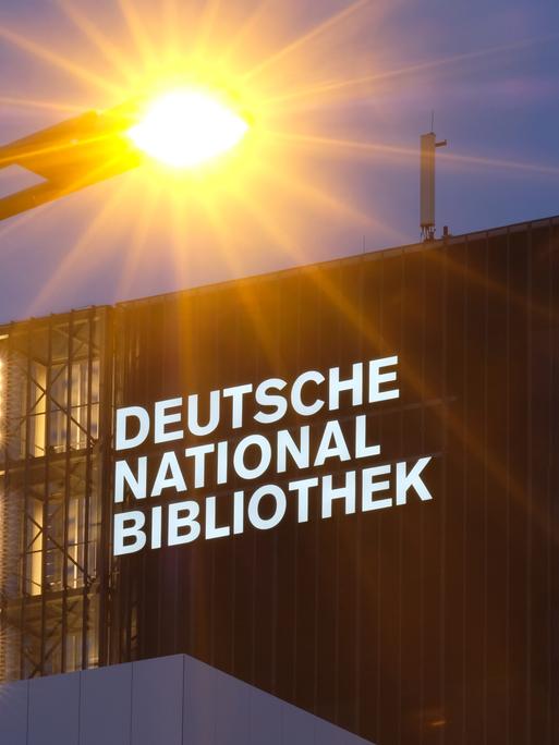 Der neue Schriftzug "Deutsche Nationalbibliothek" leuchtet in Leipzig an einem 55 Meter hohen Gebäude der früheren Deutschen Bücherei mit einer Straßenlaterne im Vordergrund. 