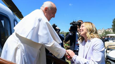 Georgia Meloni (links) drückt Papst Franziskus bei dessen Ausstieg aus einem Hubschrauber die Hand. 