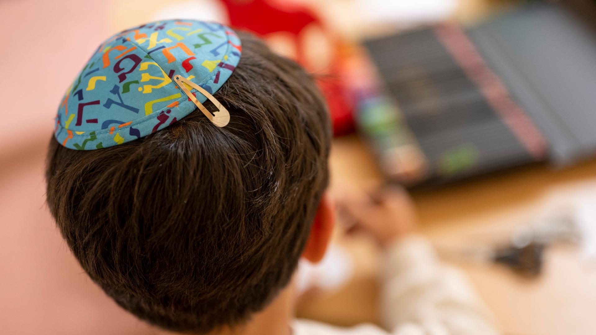 Ein Junge mit einer Kippa auf dem Kopf sitzt an einem Bastelstand beim Jüdischen Straßenfest in Potsdam.