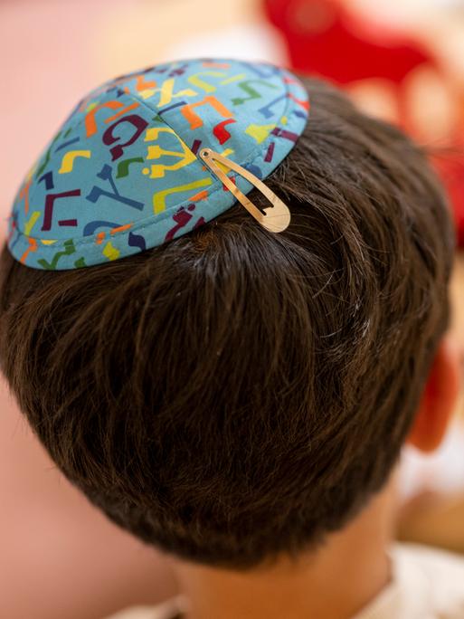 Ein Junge mit einer Kippa auf dem Kopf sitzt an einem Bastelstand beim Jüdischen Straßenfest in Potsdam.