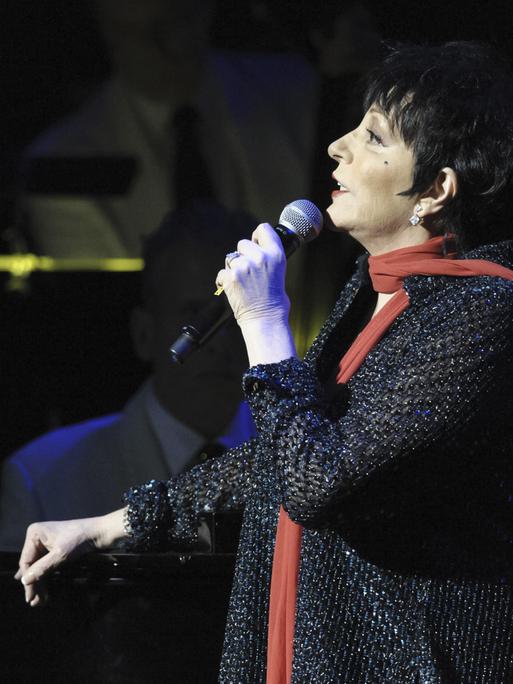 Liza Minnelli im Profil wie sie in ein Mikrofon singt