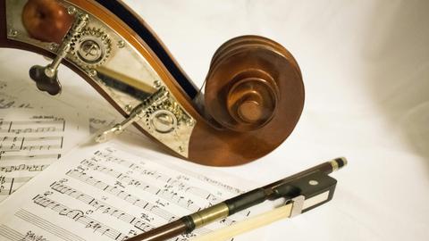 Die Schnecke einer Geige liegt auf Noten, daneben liegt noch der Bogen des Instrumentes. Die Schnecke einer Geige liegt auf Noten, daneben liegt noch der Bogen des Instrumentes.