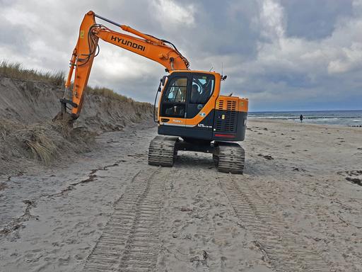 Nach der schweren Sturmflut vom 20. und 21.Oktober 2023 werden die Schaeden sichtbar - ein Bagger glättet die beschädigten Dünen am Ostseestrand in Zingst.