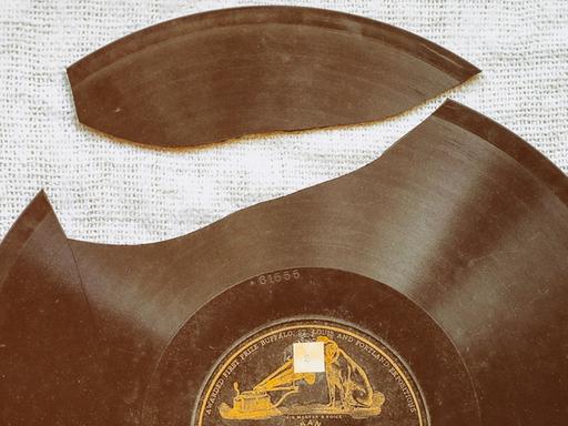 Blick auf eine historische Vinyl-Platte, aus der ein großes Stück herausgebrochen ist.