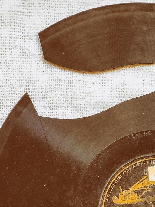 Blick auf eine historische Vinyl-Platte, aus der ein großes Stück herausgebrochen ist.