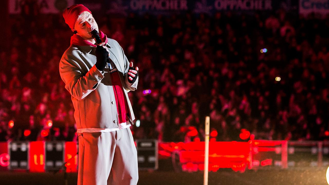 Der Sänger Alexander Knappe steht auf einer Bühne im Stadion. 