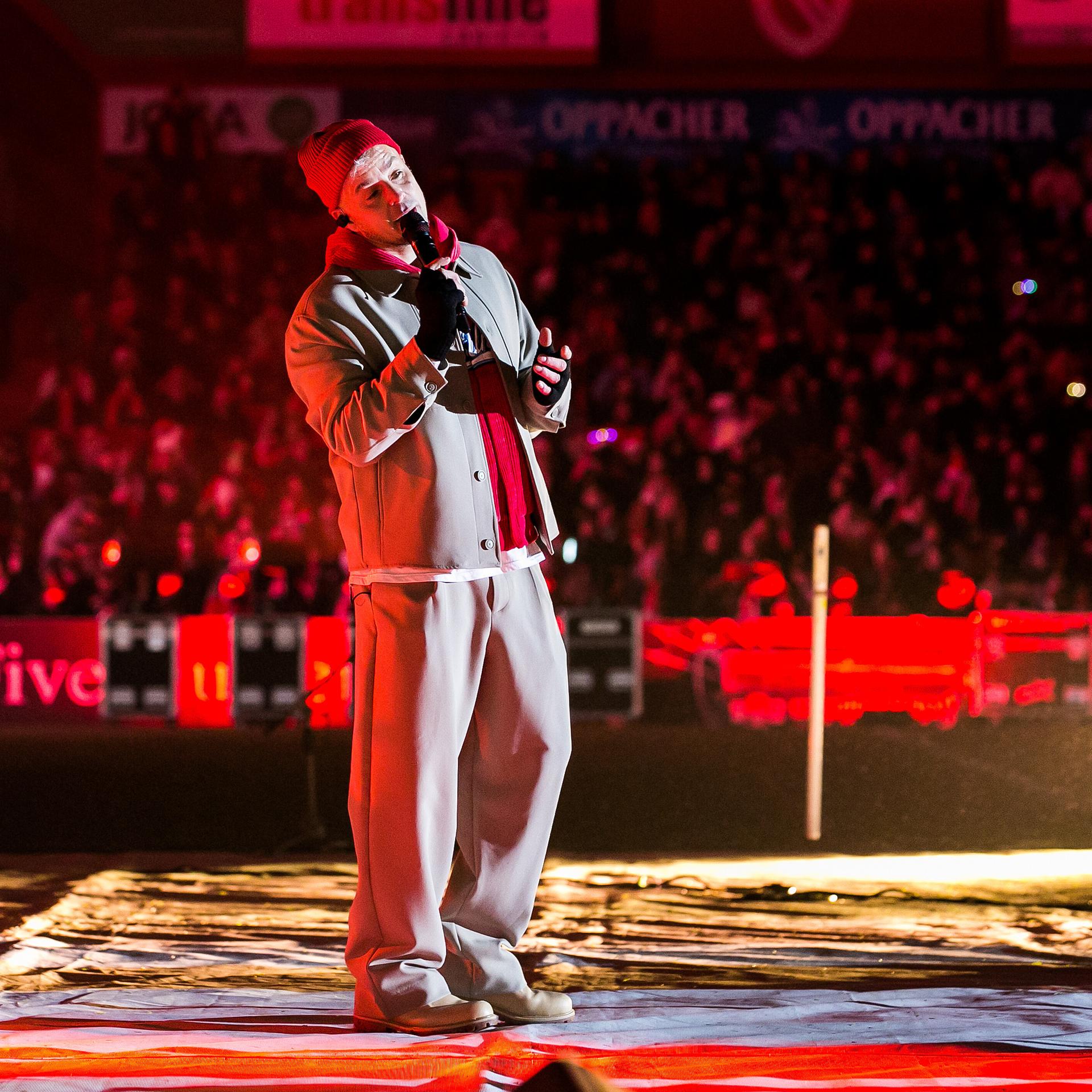 Der Sänger Alexander Knappe steht auf einer Bühne im Stadion. 