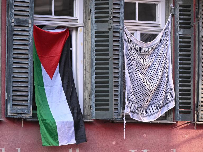Palästinaflagge und Palästinensertuch in zwei Fenstern am Tübinger Holzmarkt
