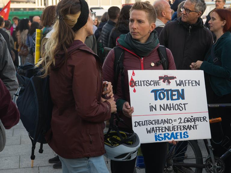 Person hält bei Demo "Für einen gerechten Frieden in Palästina und Israel" ein Schild mit der Aufschrift "DEUTSCHE WAFFEN TÖTEN IN NAHOST" hoch