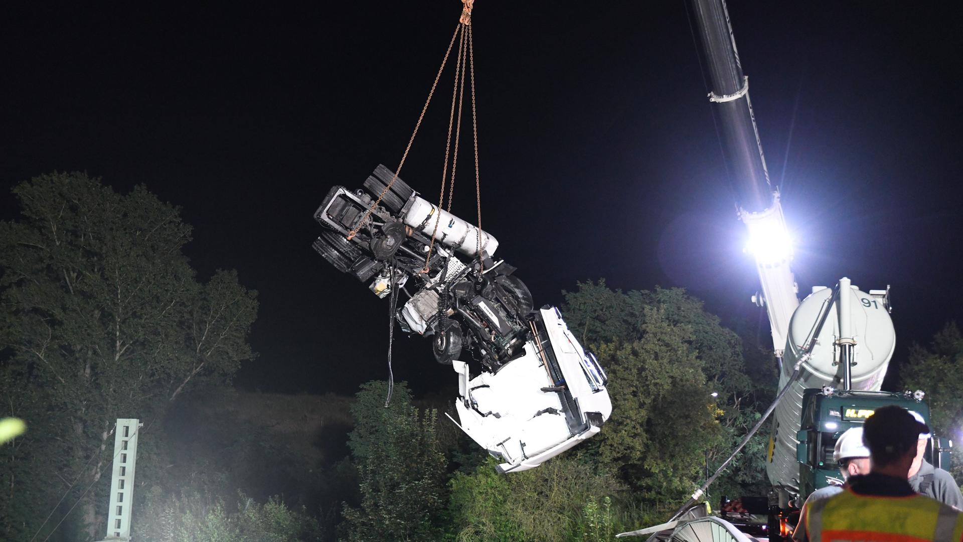 Ein Lastwagen wird nach dem Sturz von einer Brücke auf Bahngleise geborgen. 