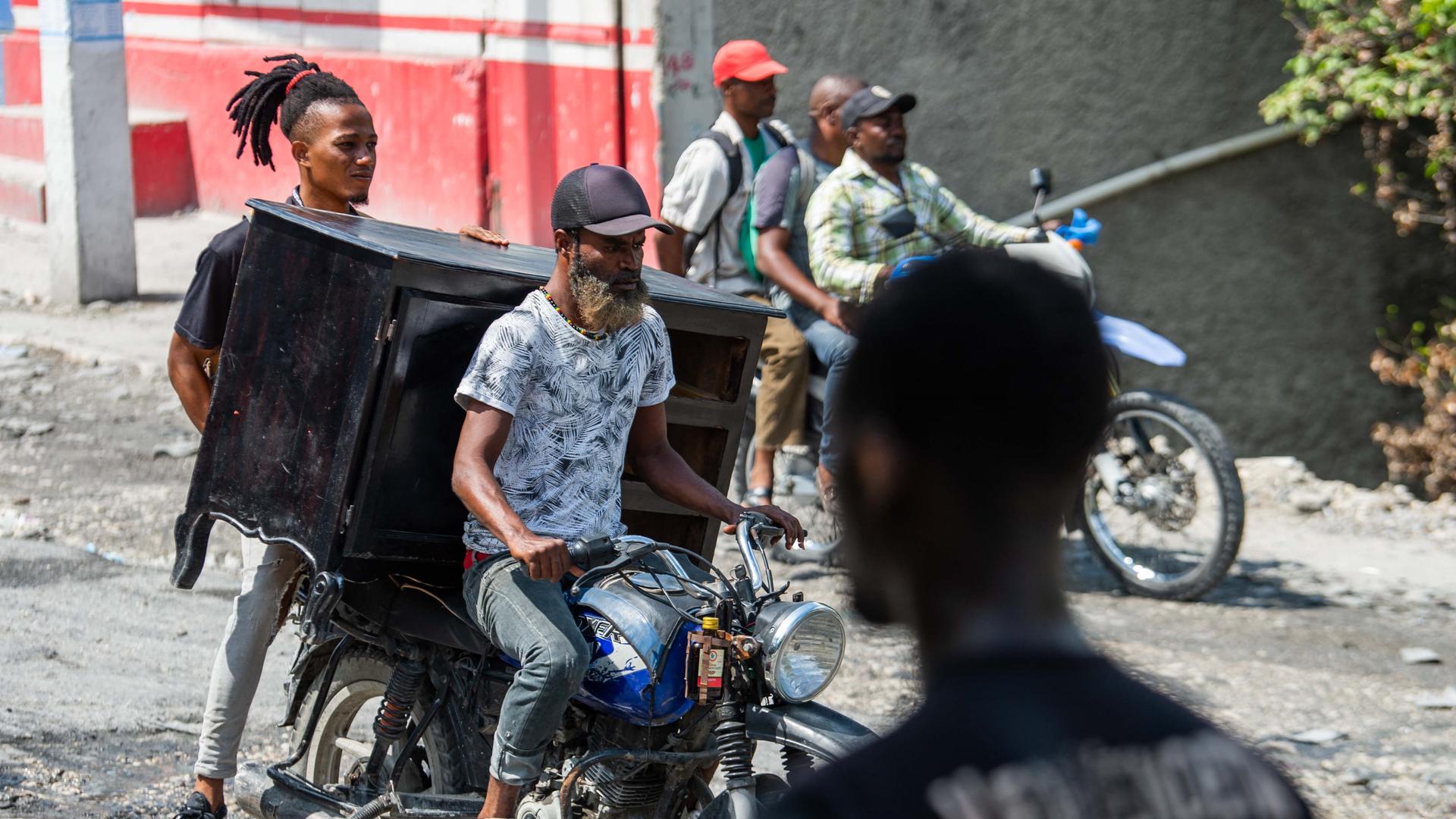 Menschen in Port-au-Prince flüchten auf Motorrädern, die voll bepackt sind mit ihren Habseligkeiten. Menschen in Port-au-Prince flüchten auf Motorrädern, die voll bepackt sind mit ihren Habseligkeiten.
