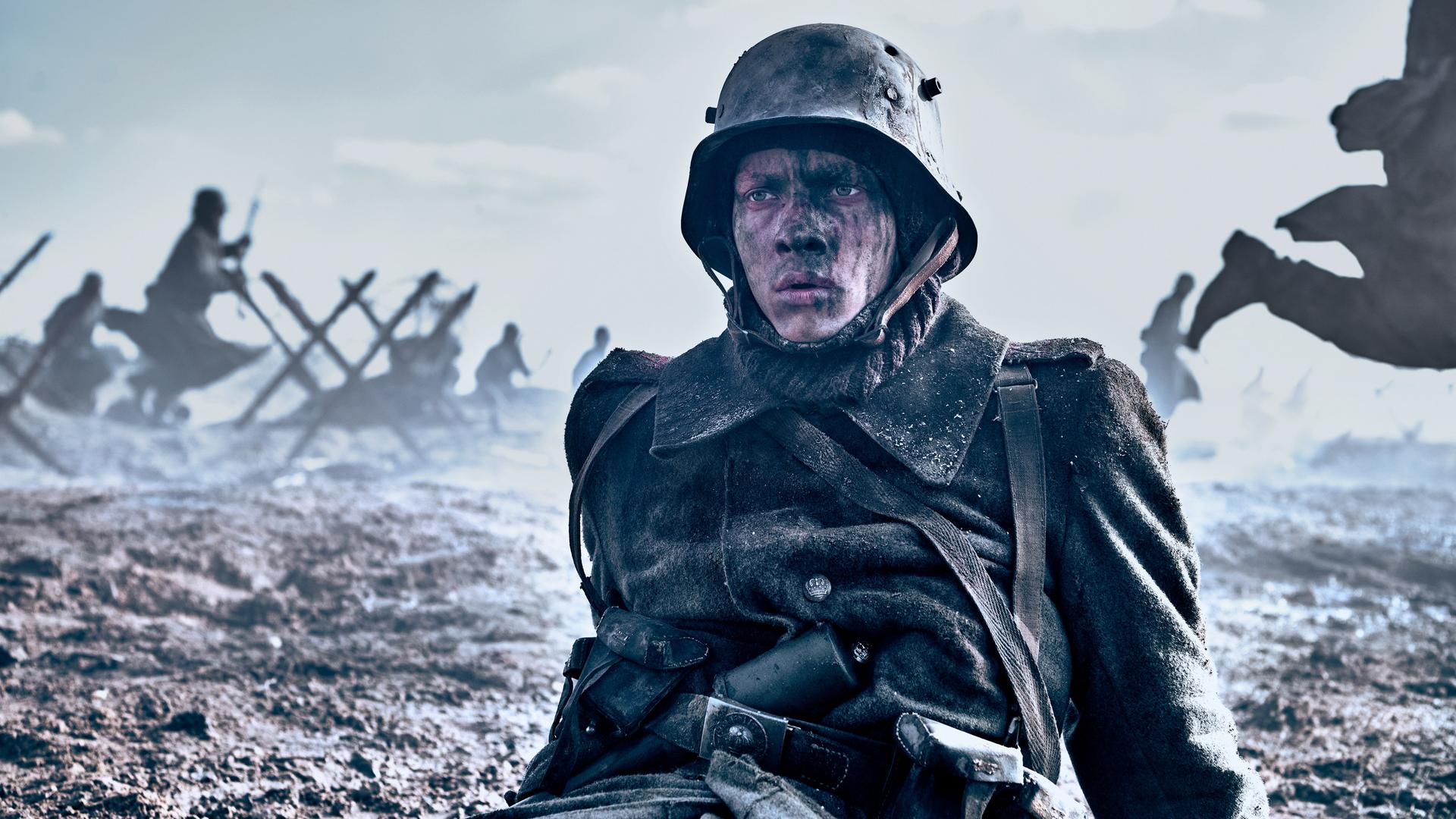 Filmszene: Ein junger Soldat in Uniform sitzt verletzt und verschmutzt auf dem Schlachtfeld.