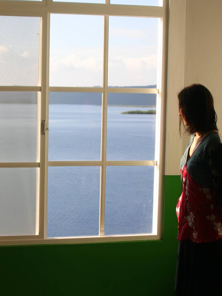 Eine Frau steht allein am Fenster. Eine Frau steht allein am Fenster.