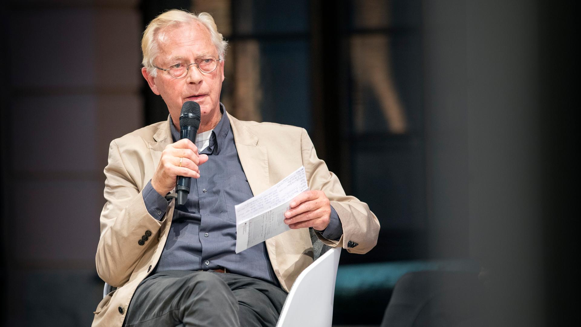 Uwe-Karsten Heye, Journalist, sitzt auf einem Stuhl und hält Unterlagen und ein Mikrofon in der Hand. Aufnahme vom 08.10.2019. Uwe-Karsten Heye, Journalist, sitzt auf einem Stuhl und hält Unterlagen und ein Mikrofon in der Hand. Aufnahme vom 08.10.2019.