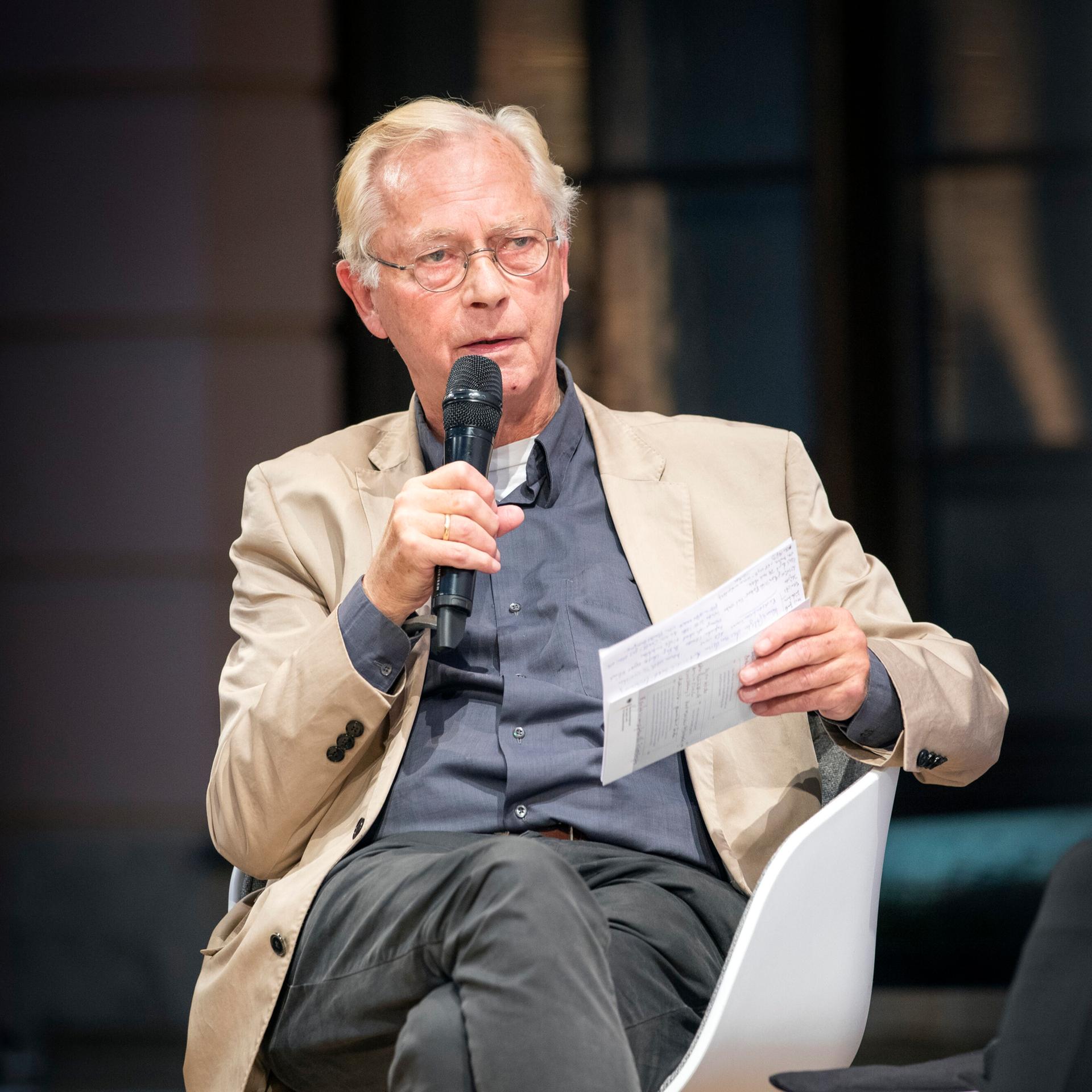 Uwe-Karsten Heye, Journalist, sitzt auf einem Stuhl und hält Unterlagen und ein Mikrofon in der Hand. Aufnahme vom 08.10.2019.