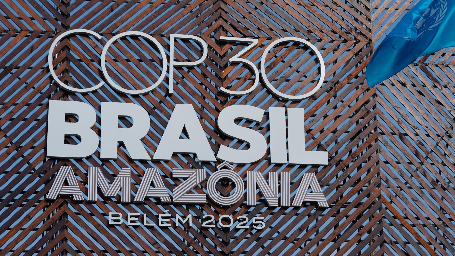 Eine Fahne der Vereinten Nationen weht neben dem Logo der Weltklimakonferenz COP30. 