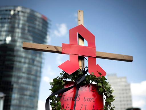 Eine Frau hält ein Kreuz in der Hand, auf dem das Apotheken-Logo angebracht ist. Eine Frau hält ein Kreuz in der Hand, auf dem das Apotheken-Logo angebracht ist.
