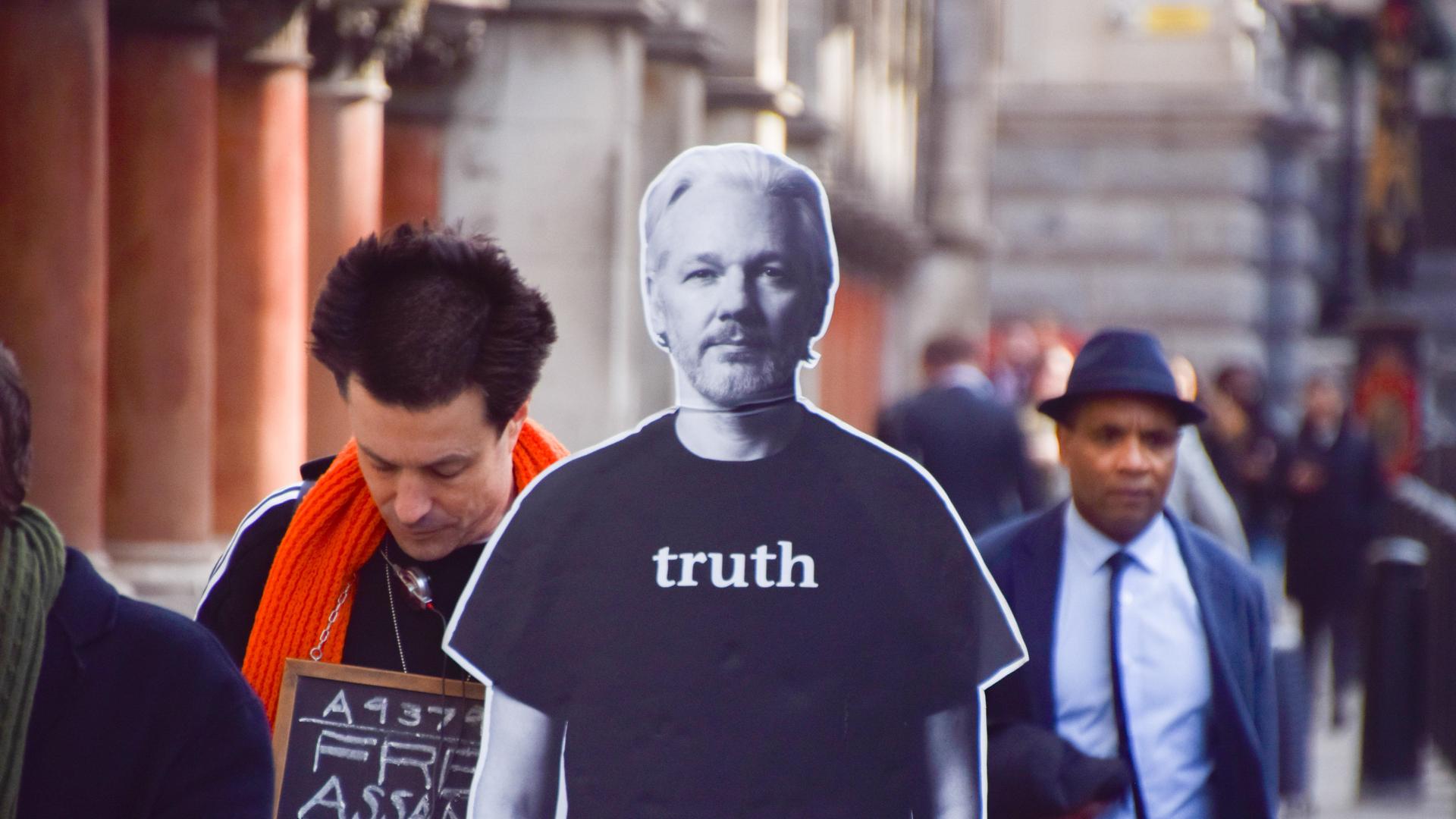 Ein Demonstrant steht außerhalb des Obersten Gerichts in London mit einem Pappaufsteller, der das Konterfei Julian Assanges hat. Auf diesem steht "Truth" - Wahrheit.