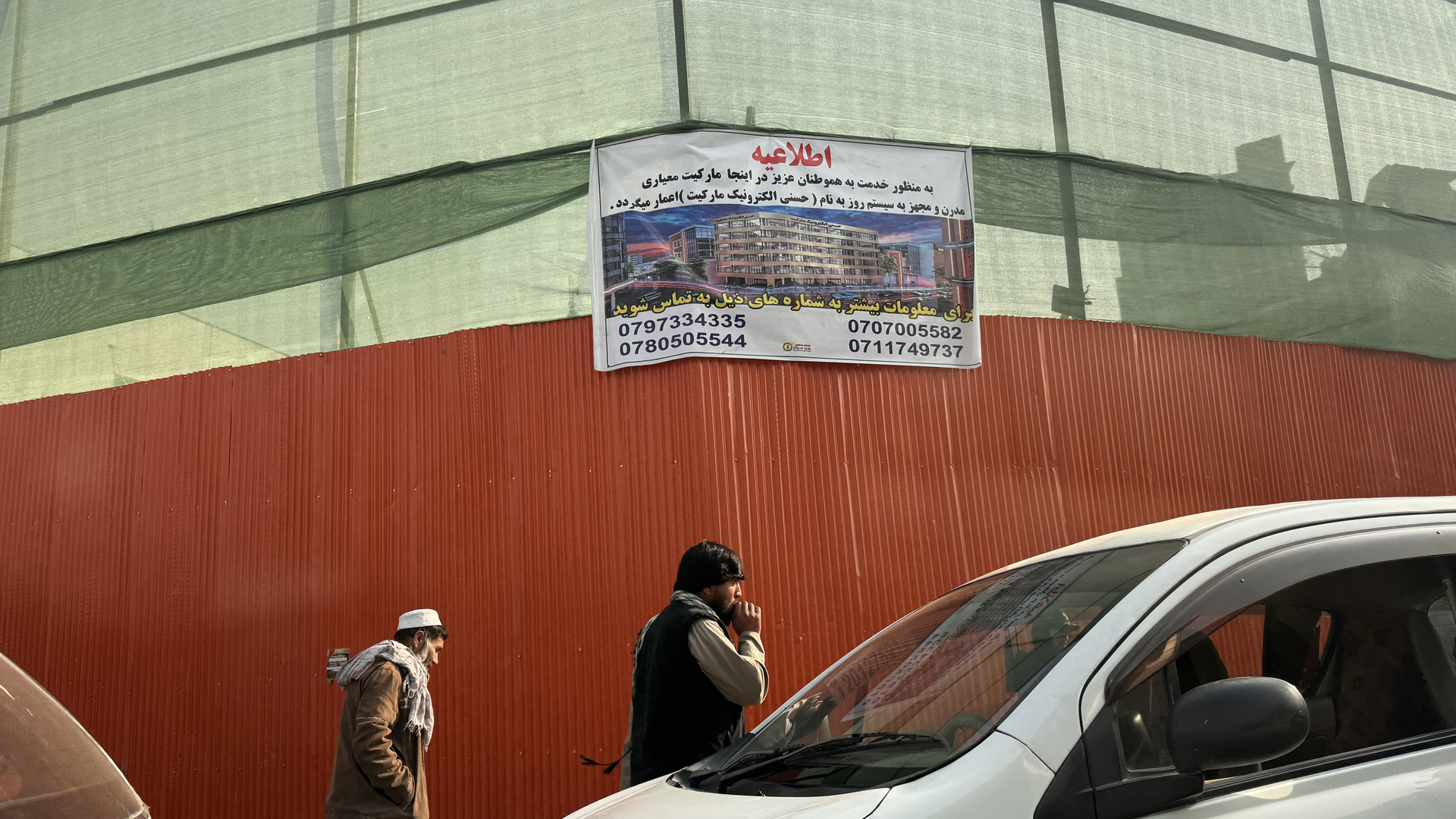 Ein Schild an einem orangenen Bauzaun an einer Straße in Kabul