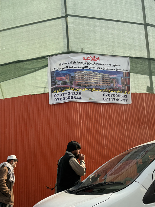 Ein Schild an einem orangenen Bauzaun an einer Straße in Kabul