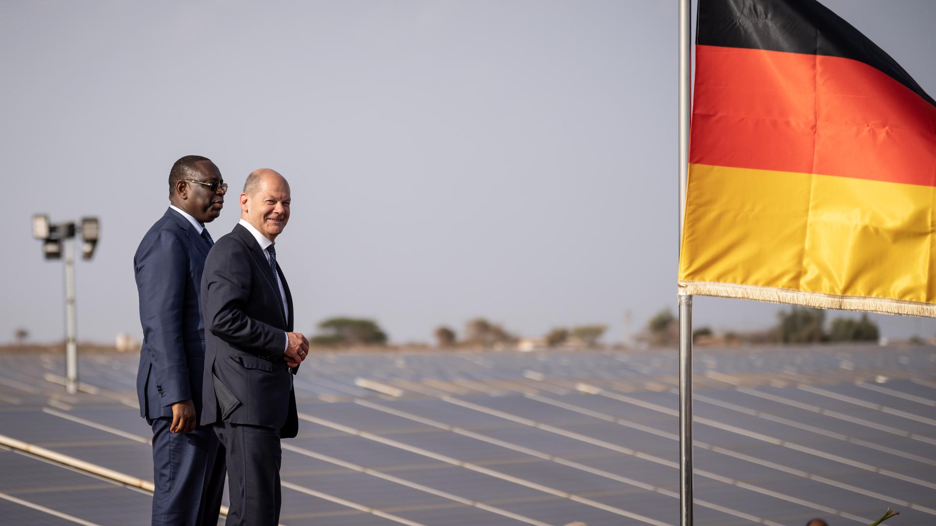 Bundeskanzler Olaf Scholz (SPD), nimmt neben Macky Sall, Präsident der Republik Senegal, an der Eröffnung einer Photovoltaikanlage in Diass teil. Neben den beiden weht die deutsche Flagge. 