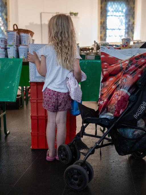 Ein Kind schaut sich in einer Ausgabestelle der Berliner Tafel die Lebensmittel an.