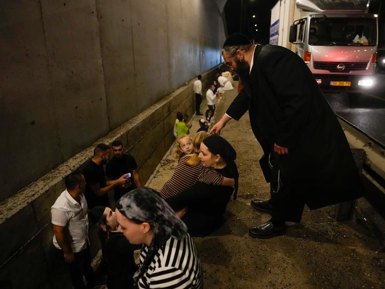 Menschen schützen sich am Rand einer Straße vor den iranischen Raketen.