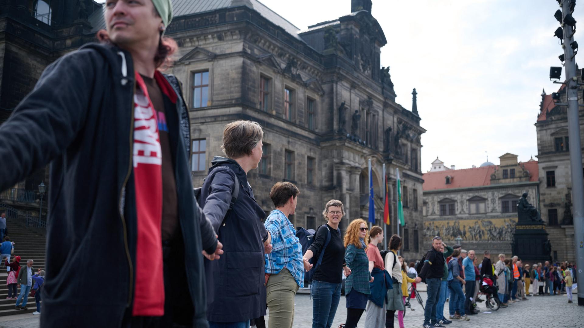Menschen stehen in Dresden nebeneinander und reichen sich die Hände. Menschen stehen in Dresden nebeneinander und reichen sich die Hände.
