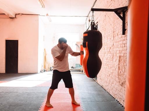 Ein Mann trainiert an einem Boxsack in einem Fitnesstudio Ein Mann trainiert an einem Boxsack in einem Fitnesstudio