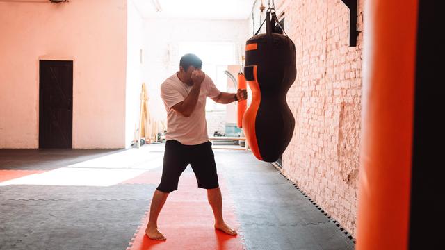 Ein Mann trainiert an einem Boxsack in einem Fitnesstudio