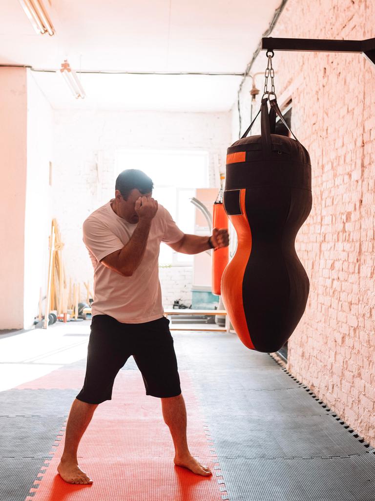 Ein Mann trainiert an einem Boxsack in einem Fitnesstudio Ein Mann trainiert an einem Boxsack in einem Fitnesstudio