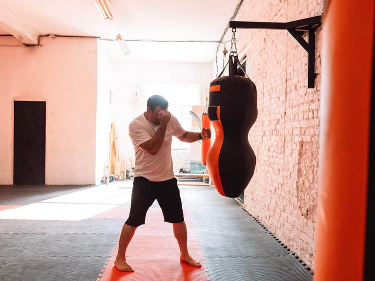 Ein Mann trainiert an einem Boxsack in einem Fitnesstudio