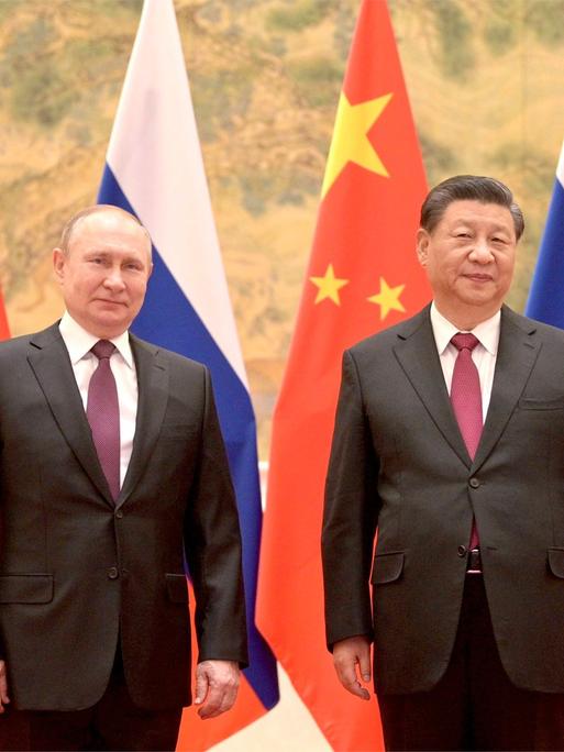Der russische Präsident Putin steht links neben dem chinesischen Präsidenten Xi, im Hintergrund sind die Fahnen Russlands und Chinas.