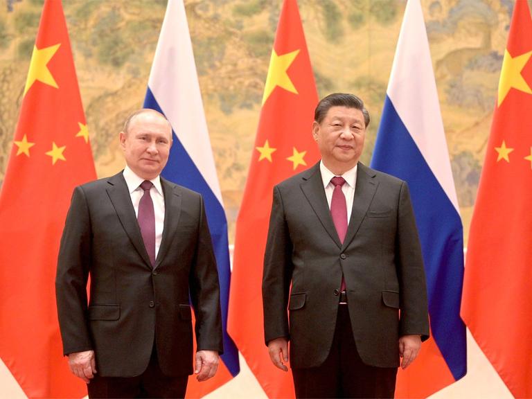 Der russische Präsident Putin steht links neben dem chinesischen Präsidenten Xi, im Hintergrund sind die Fahnen Russlands und Chinas.