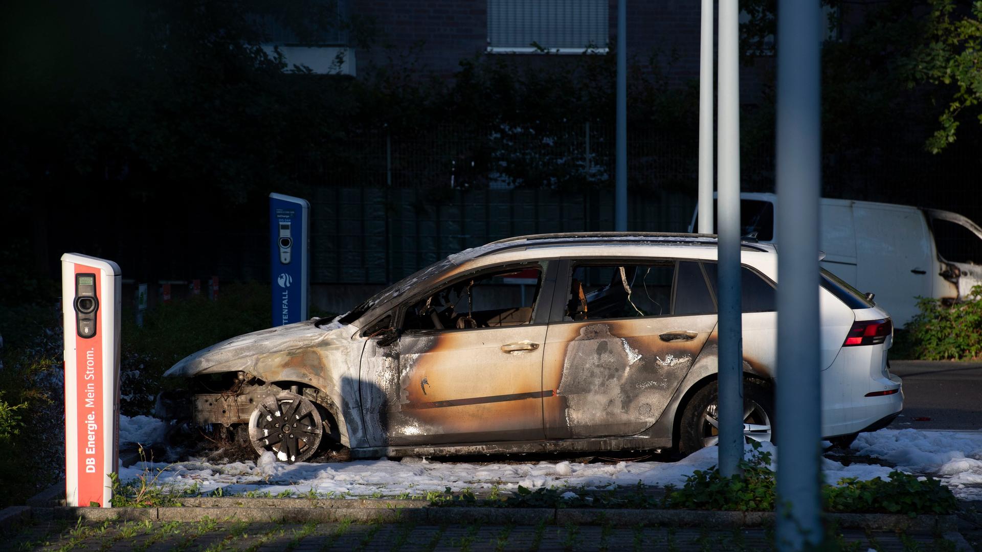 Berlin: Zwei ausgebrannte Fahrzeuge stehen auf einem Parkplatz an der Caroline-Michaelis-Straße in Berlin-Mitte. Die Unbekannten sprühten den Schriftzug "Stop Tren Maya" an die Scheibe eines Gebäudes.