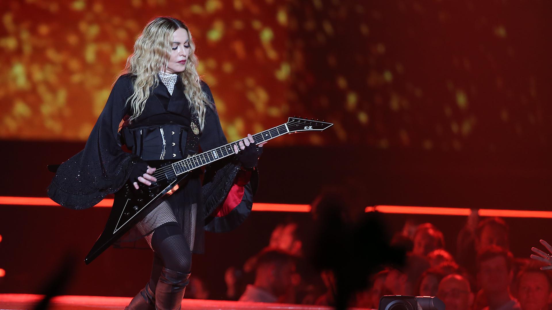 Madonna steht am 04.11.2015 in Köln mit Gitarre und in schwarz gekleidet auf der Bühne.