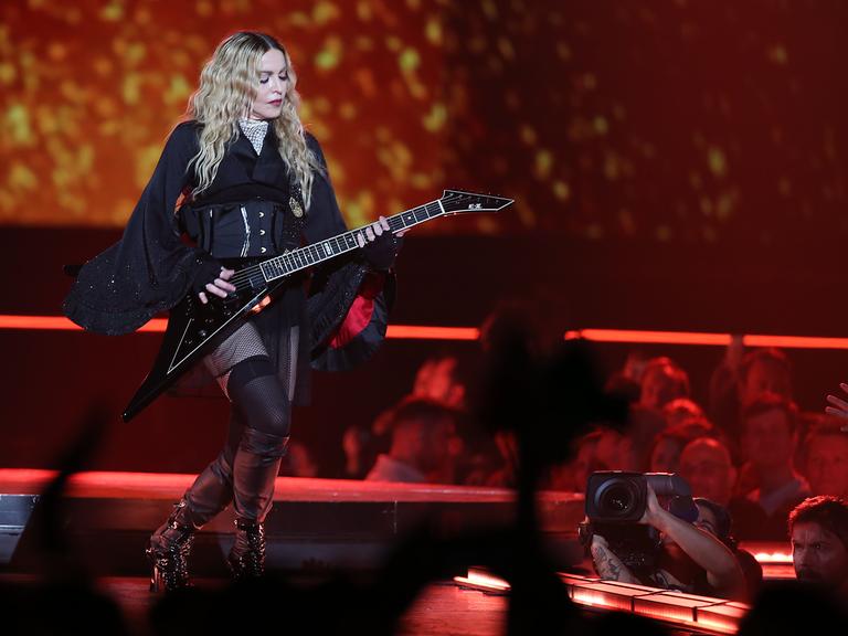 Madonna steht am 04.11.2015 in Köln mit Gitarre und in schwarz gekleidet auf der Bühne.