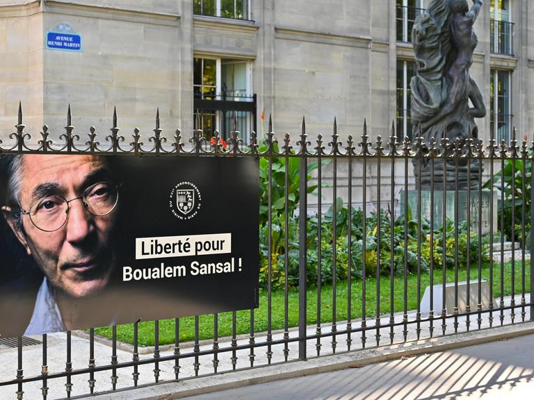 Ein Poster mit einem Porträt von Boualem Sansal und den Worten "Liberté pour Boualem Sansal!" hängt an einem Zaun im 5. Arrondissement in Paris. 